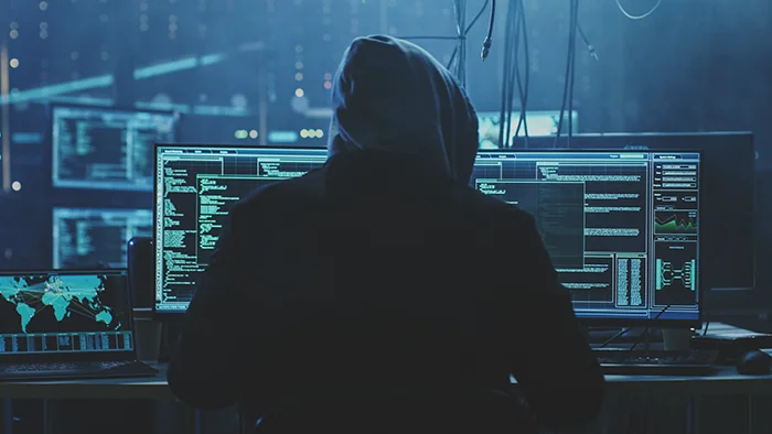 Editorial illustration of server racks and a fractured glass shield representing cybersecurity vulnerabilities